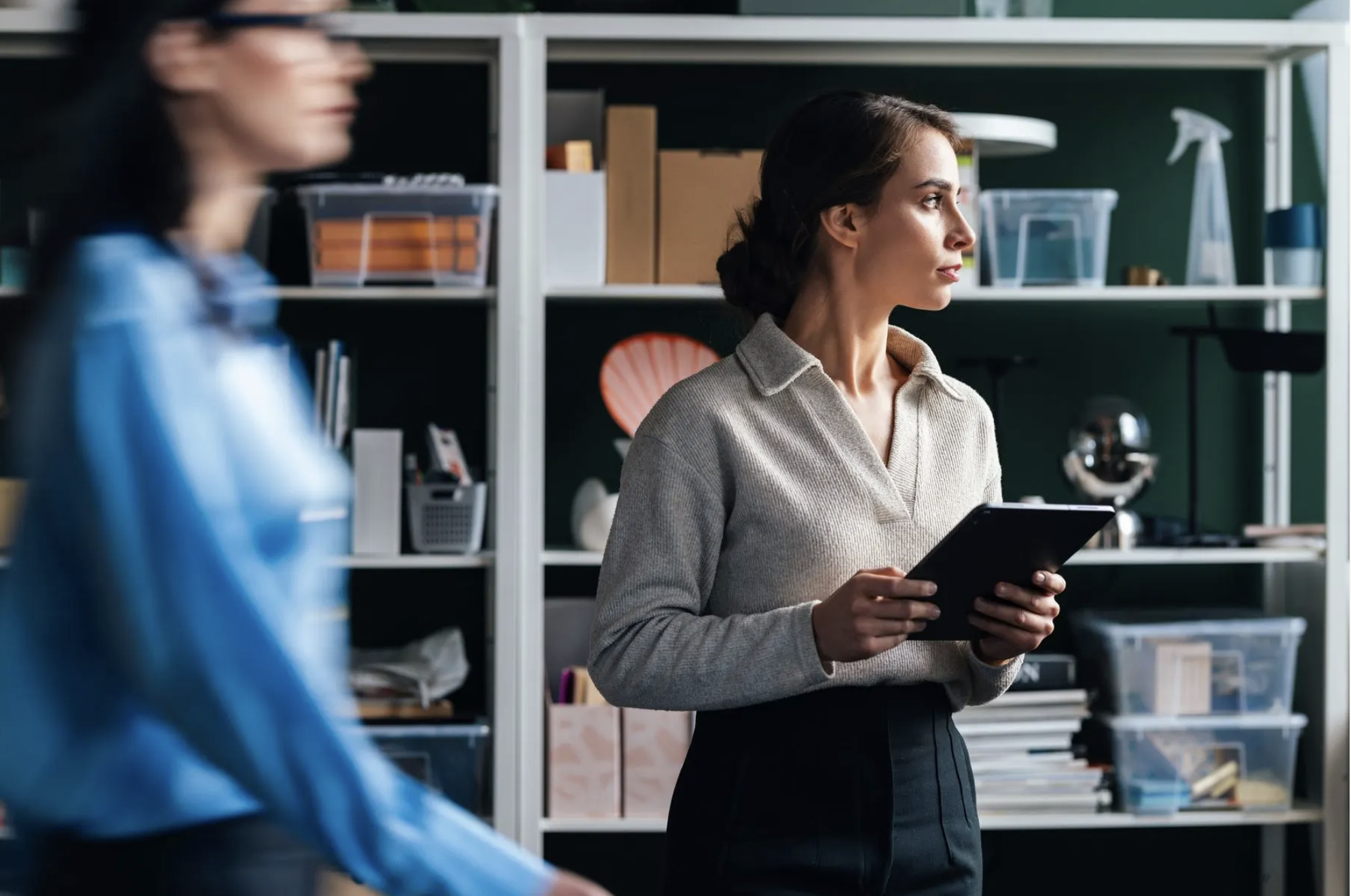 Business customer holding a tablet in front of office shelving.